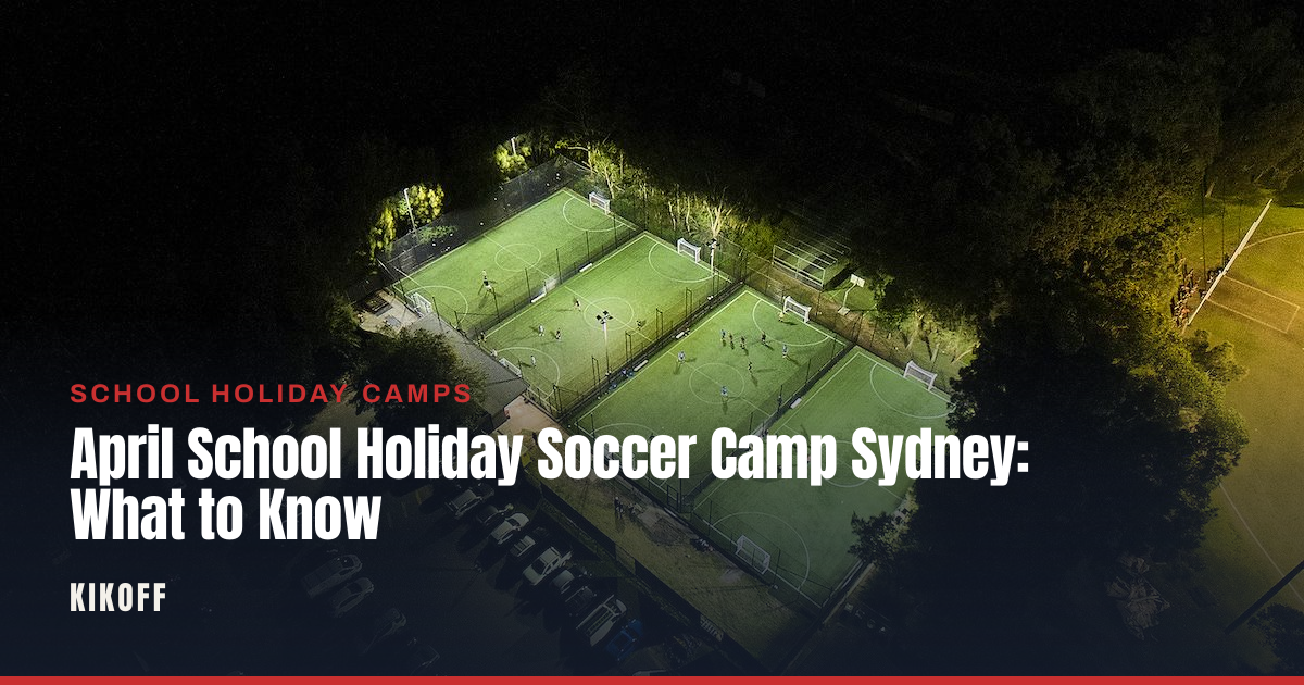 Kids in shin pads and boots playing a small-sided football drill on a caged synthetic pitch during a school holiday camp