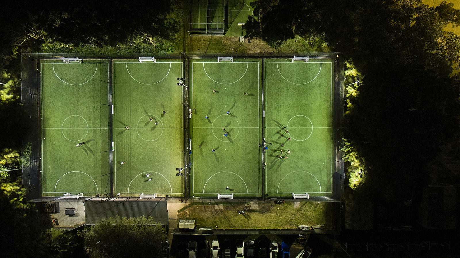 Kids in shin pads and socks lining up for a weeknight game on a synthetic pitch at KIKOFF.