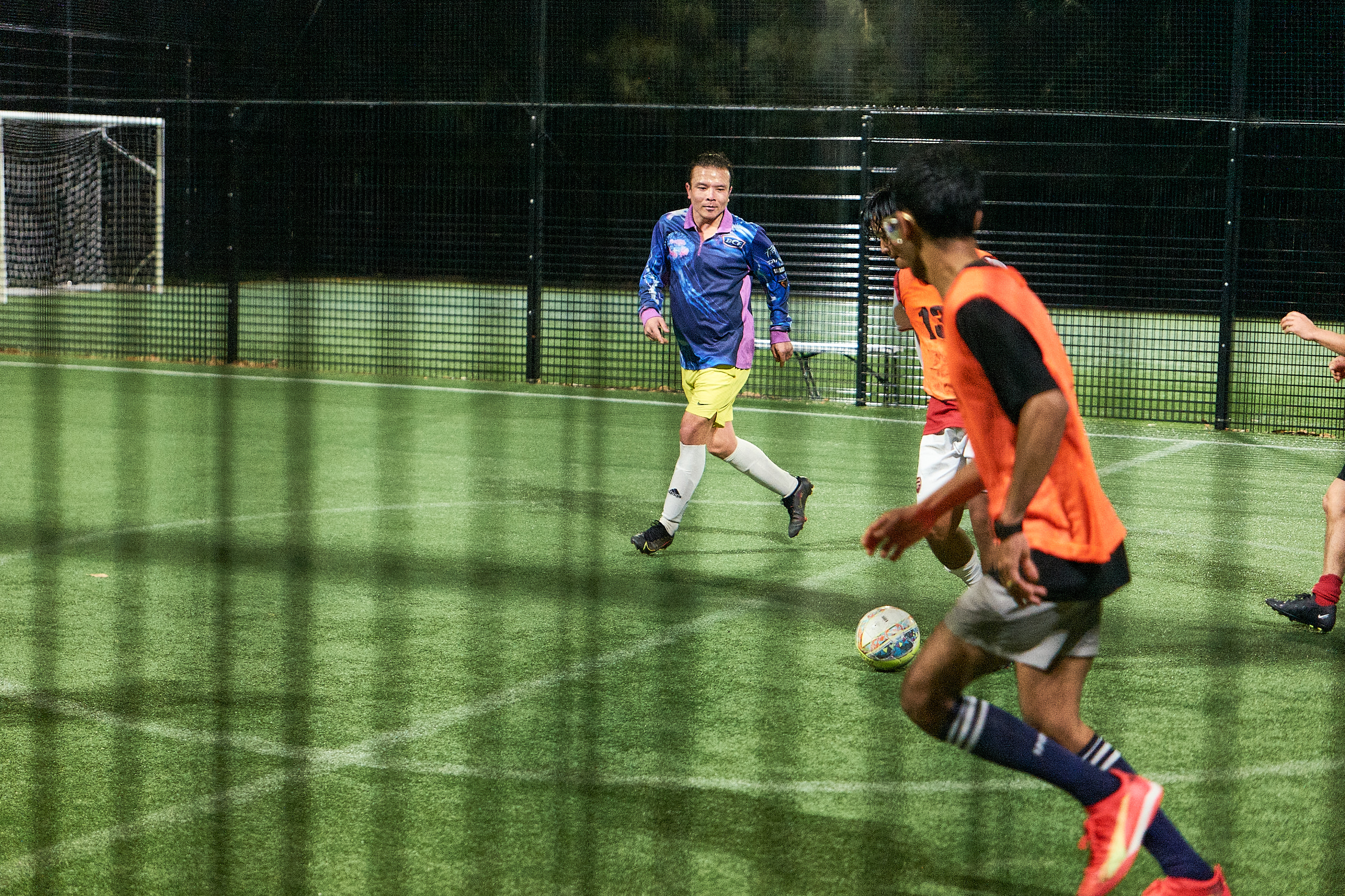 Players celebrating a goal inside the cage with futsal line markings at the Curl Curl venue.